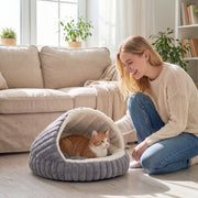 Ginger and white cat sitting in the PawHut cat cave bed in a living room