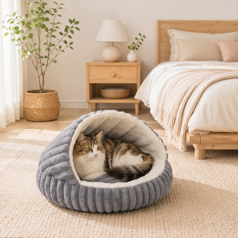 Tabby cat curled up in the cat cave bed beside a bed in a bedroom