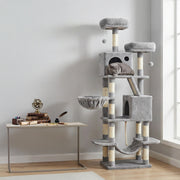 Light grey cat tree beside a desk with a grey cat asleep in the upper cave