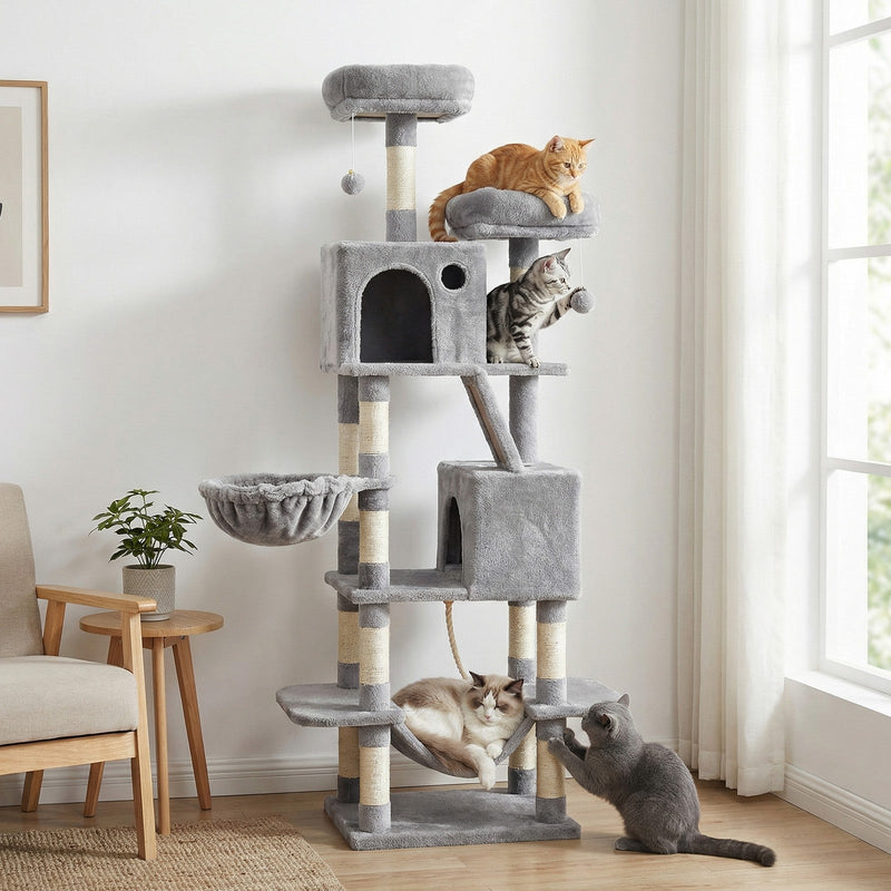 Four cats using the light grey cat tree next to an armchair and houseplant