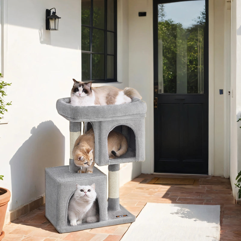 Three cats resting in the caves and on the top perch of the grey cat tree on a porch