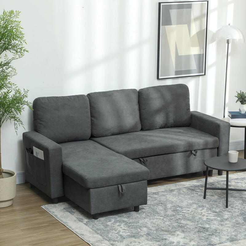 Charcoal grey L-shaped sofa bed styled in a living room with a plant and floor lamp