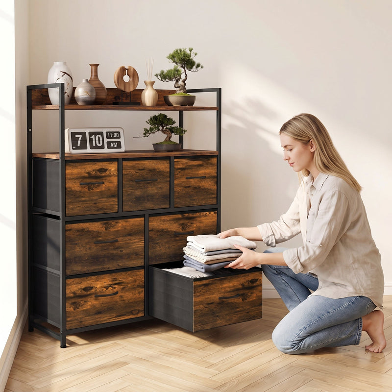 Woman kneeling to fold clothes in a pulled-out fabric drawer of the rustic brown chest of drawers