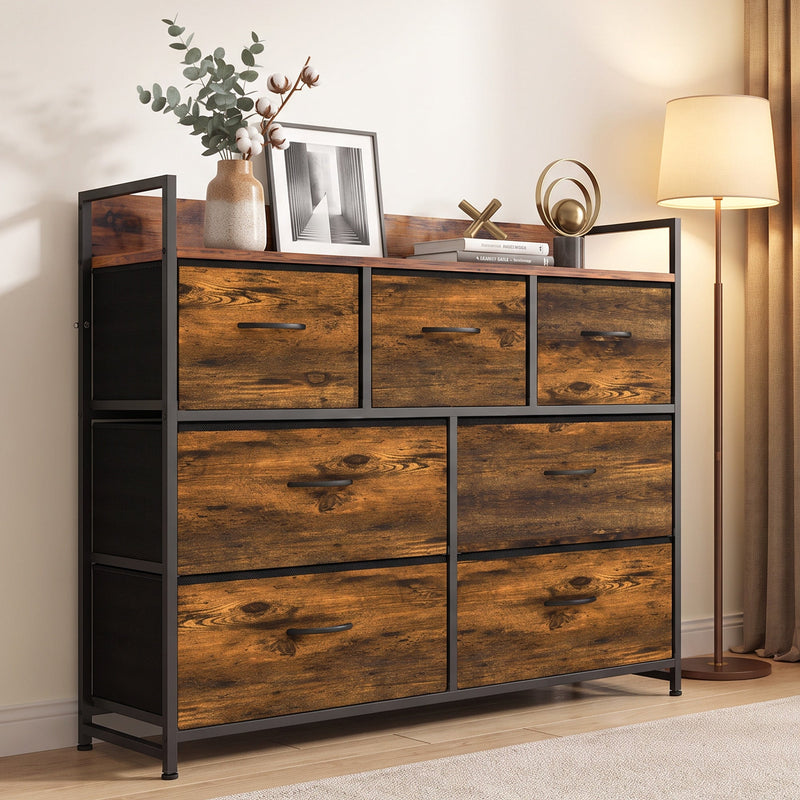 Rustic brown 7-drawer chest of drawers in a living room with a plant and framed art on the top shelf