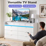White chest of drawers used as a TV stand holding a 65 inch TV
