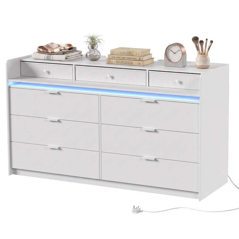 White chest of drawers on a plain background with books, clock and brushes on top
