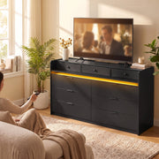 Black chest of drawers under a TV in a living room with a warm LED glow