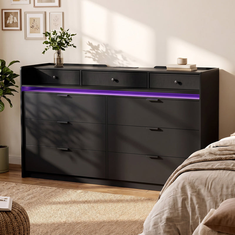 Black chest of drawers with purple LED strip beside a bed