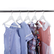 Children's shirts and dresses on white wooden hangers on a rail