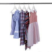 Girls' dresses and a checked shirt hung on white hangers on a metal rail