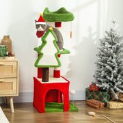 Grey cat in a Santa hat on the top perch beside a snow-flocked Christmas tree