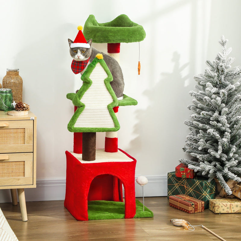 Grey cat in a Santa hat on the top perch beside a snow-flocked Christmas tree