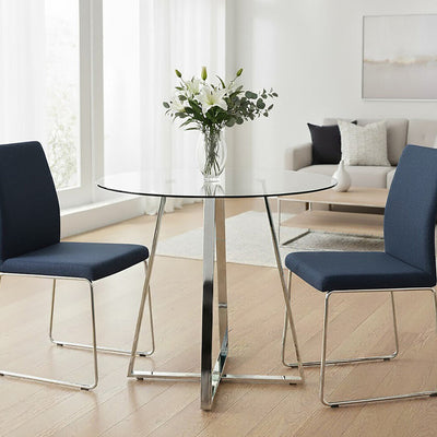 Clear glass round dining table with silver metal base styled in a modern living space