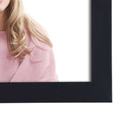 Close-up of the black frame moulding beside a model in a pink jumper