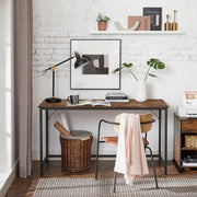 Computer desk against a white brick wall with a lamp, books and a chair