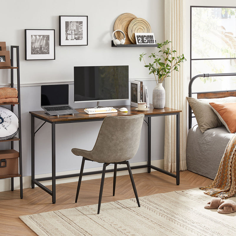 Computer desk with a monitor set up in a bedroom corner beside a bed