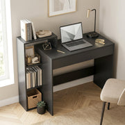 Black desk with a laptop and books in a home office beside a window