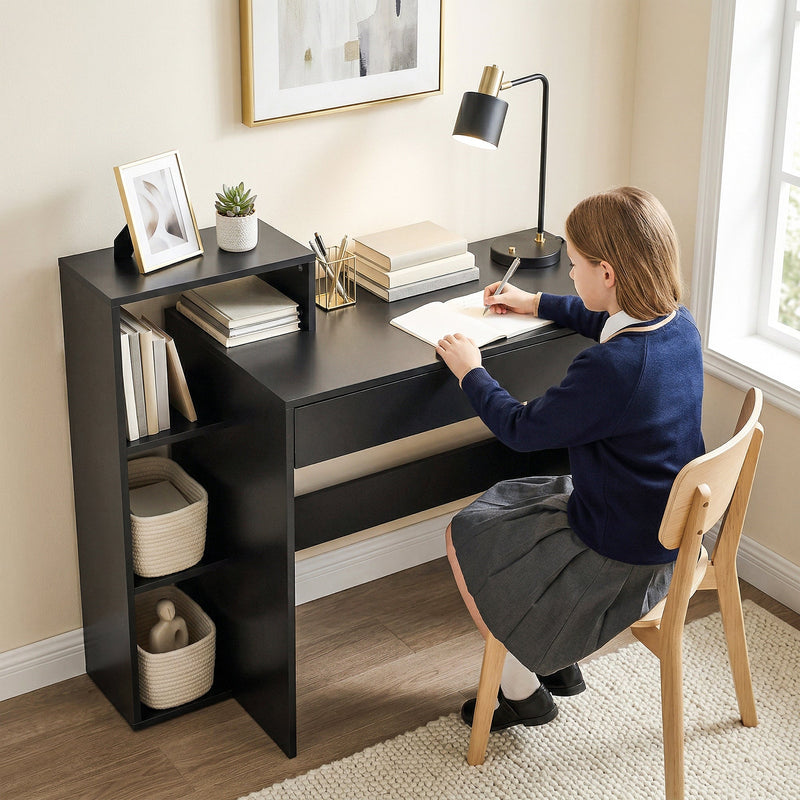 Student writing at the black desk on a wooden chair beside a window