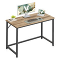 Vasagle computer desk in camel brown and ink black styled with a monitor, laptop and keyboard