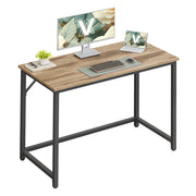 Vasagle computer desk in camel brown and ink black styled with a monitor, laptop and keyboard