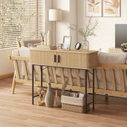 Console table behind a sofa holding a lamp, books, photo frames and a basket underneath