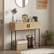 Console table in a hallway beside boots and a basket, with a round mirror above