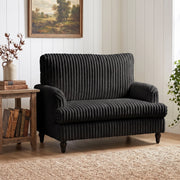 Armchair in a cottage-style room beside stacked old books and a landscape painting