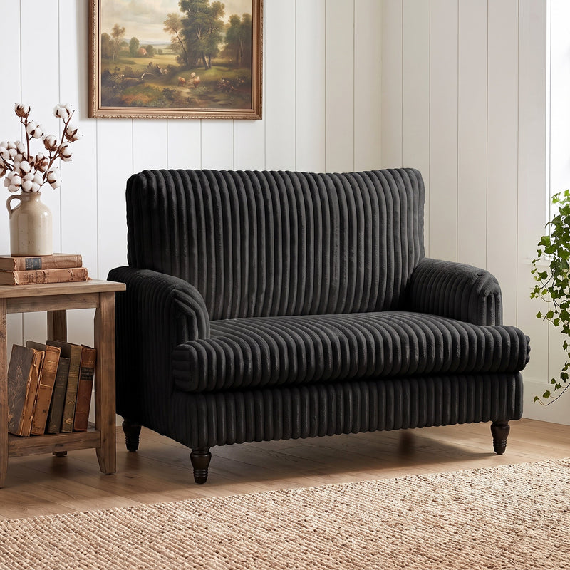 Armchair in a cottage-style room beside stacked old books and a landscape painting