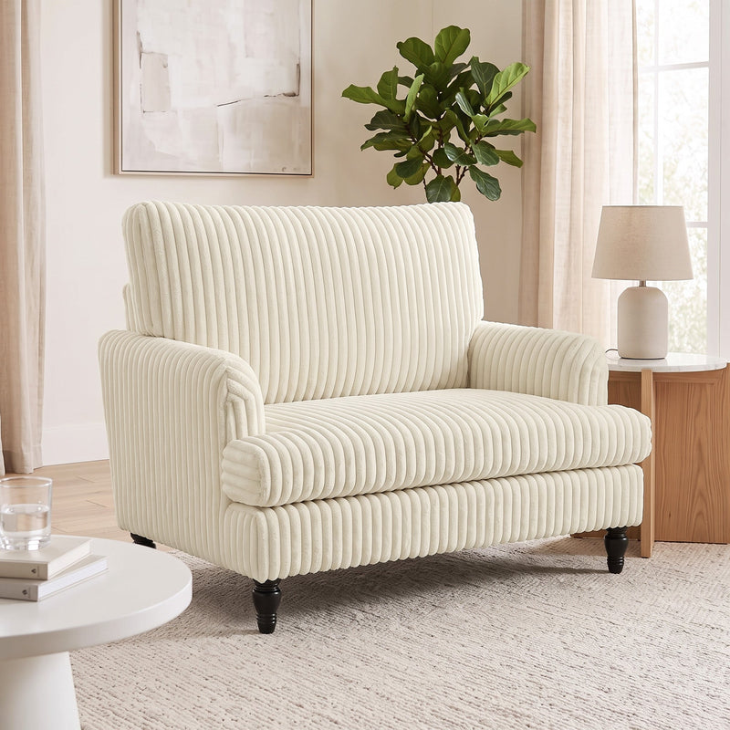 Corduroy armchair in a living room beside a table lamp and a large houseplant