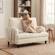 Woman sitting cross-legged in the corduroy armchair holding a retriever puppy