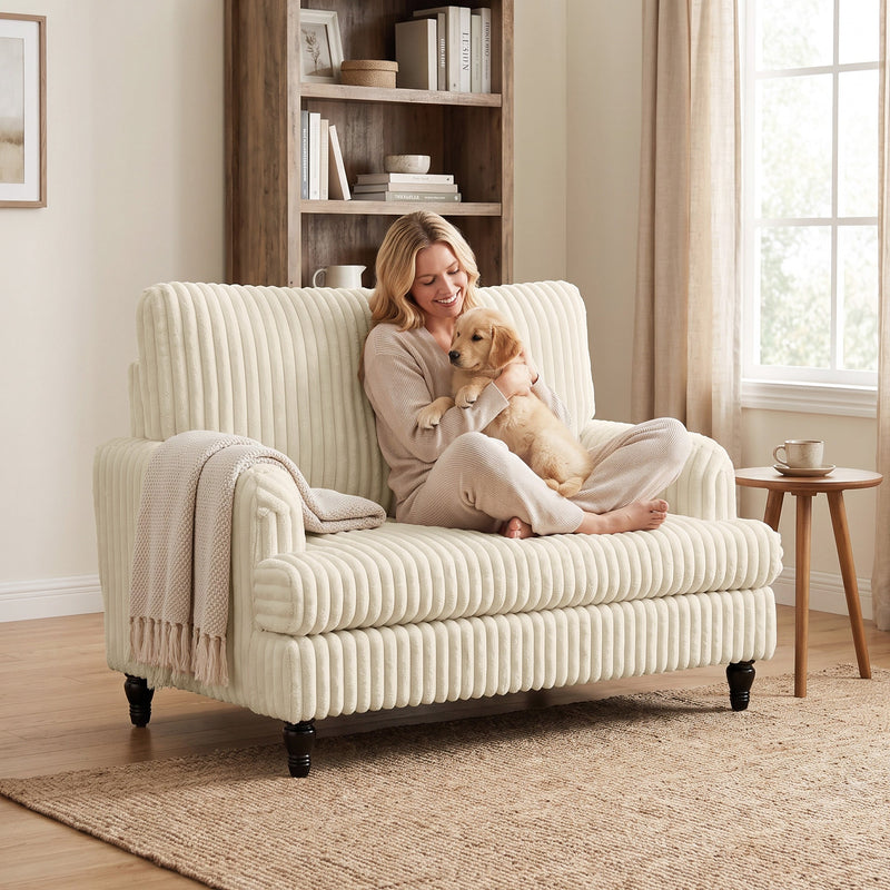 Woman sitting cross-legged in the corduroy armchair holding a retriever puppy