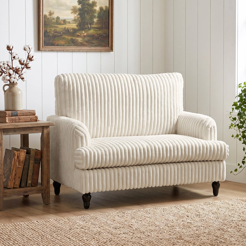 Corduroy armchair against a panelled wall below a framed landscape painting