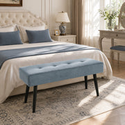 Blue tufted bench at the end of a bed in a bedroom