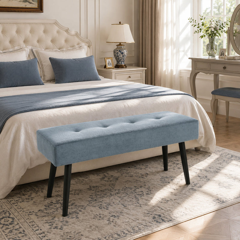 Blue tufted bench at the end of a bed in a bedroom