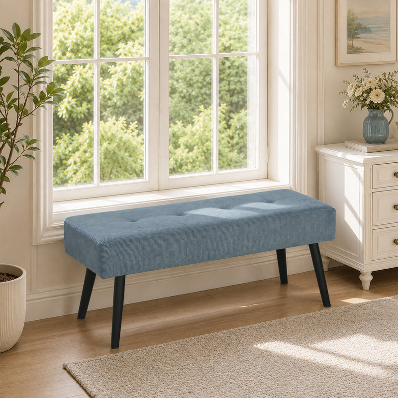 Blue bench used as a window seat below a bright living room window