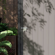 Close-up of the door latch on the grey corrugated panels with leaf shadows across them