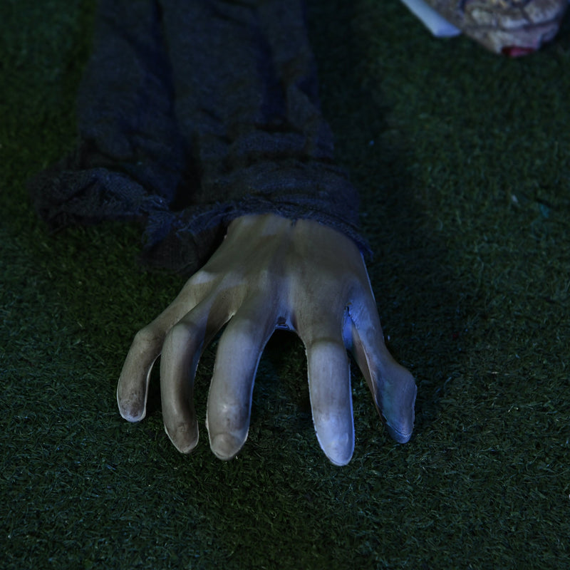 Close-up of the crawling zombie prop's pale outstretched hand resting on grass