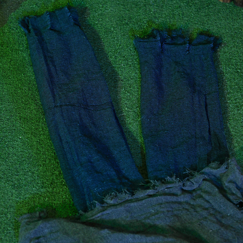 Close-up of the denim legs and grey fabric body of the crawling zombie prop on grass