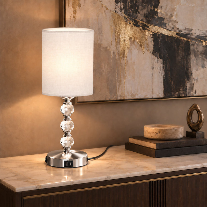 Crystal lamp lit on a sideboard with books, a small bowl and abstract art behind