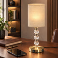 Crystal table lamp lit on a wooden desk beside a notebook and phone