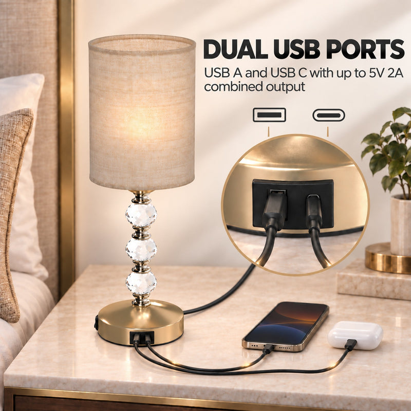 Dual USB ports graphic with a phone and earbuds charging from the lamp base on a bedside table
