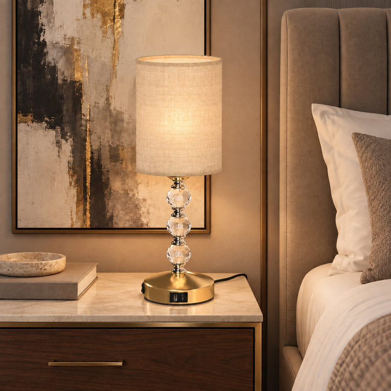 Lamp on a bedside table next to a bed with an upholstered headboard
