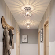 Corridor lit by two crystal ceiling lights with a coat rack on the wall
