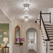 Bright hallway with two crystal ceiling lights above a staircase and arched door