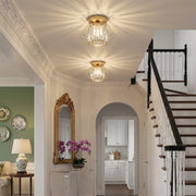 Two crystal ceiling lights in an entrance hall beside a staircase and arched doorway