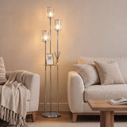 Chrome floor lamp with glass shelf beside a sofa and coffee table in a living room