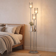Chrome 3-light floor lamp lit beside a bed in a bedroom