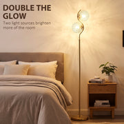 Gold two-head floor lamp glowing beside a bed with the text Double the Glow