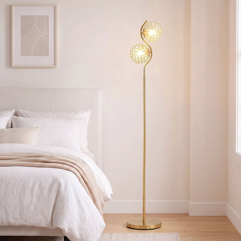Gold crystal globe floor lamp lit beside a white bed in a bright bedroom