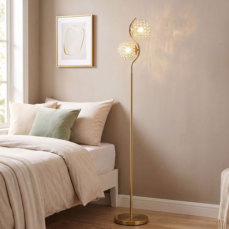 Gold crystal globe floor lamp in a bedroom corner next to a bed and window